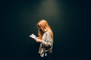 Woman reading magazine dark background