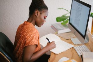 Woman writing in front of computer - Photo by Retha Ferguson from Pexels