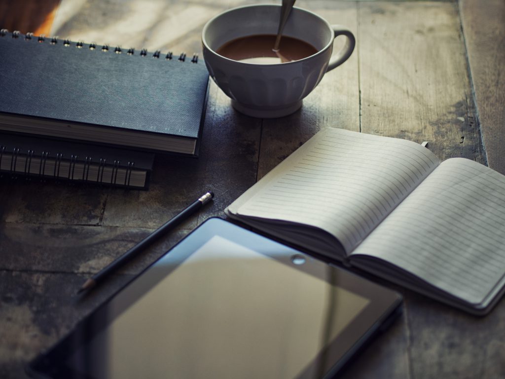 iPad open blank journal pile of journals coffee in white cup