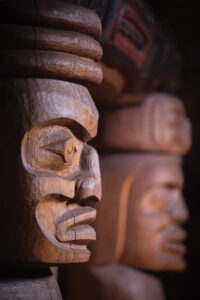 Carved Corner posts from the Wuikinuxv bighouse look out over the central fire pit. | Photo: ©Grant Callegari, Hakai Magazine