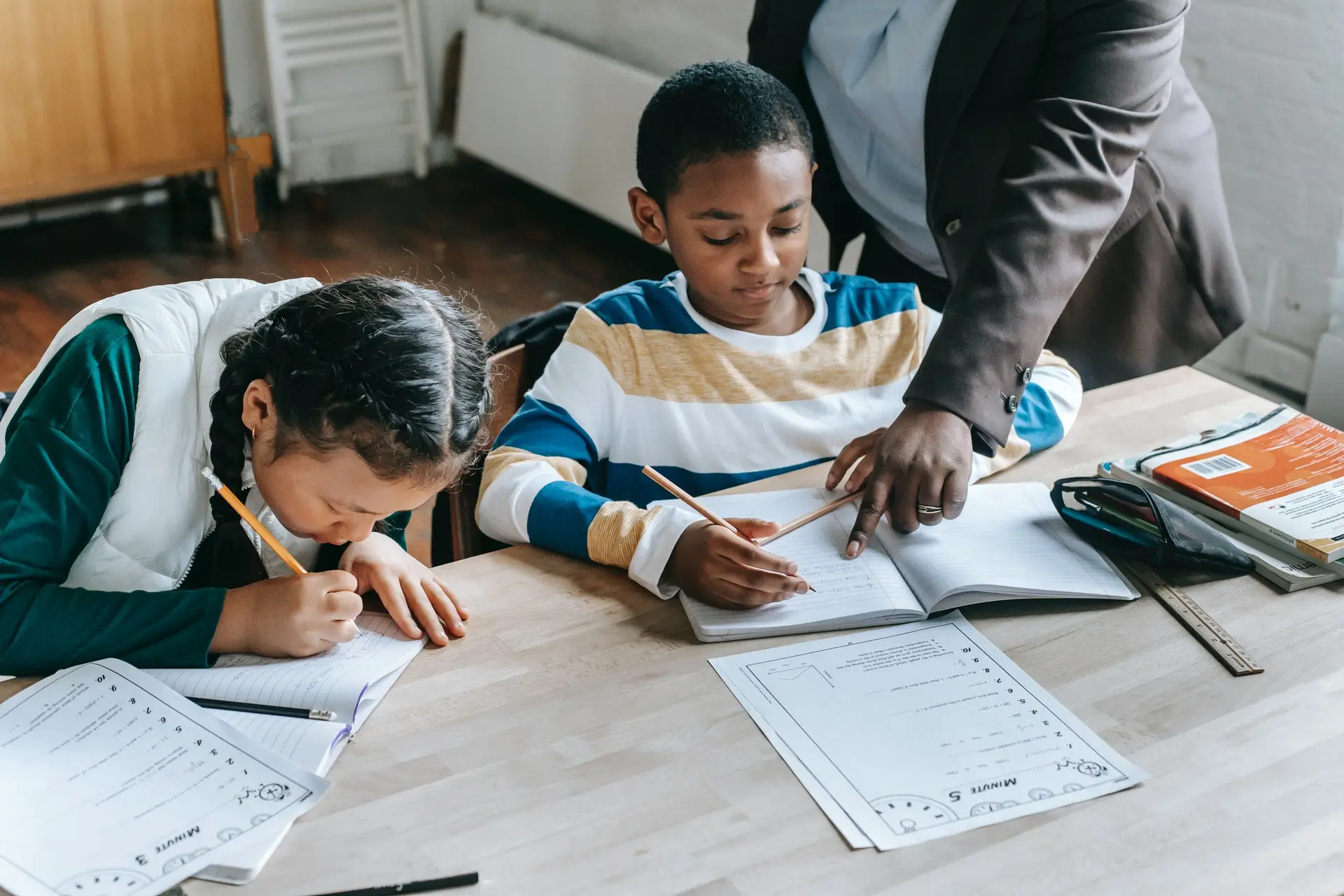 Two kids doing classwork with arm pointing to exercise book