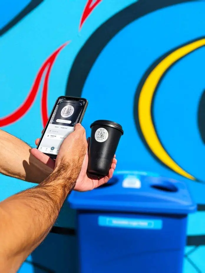 Hand holding phone scanning QR code on cup.