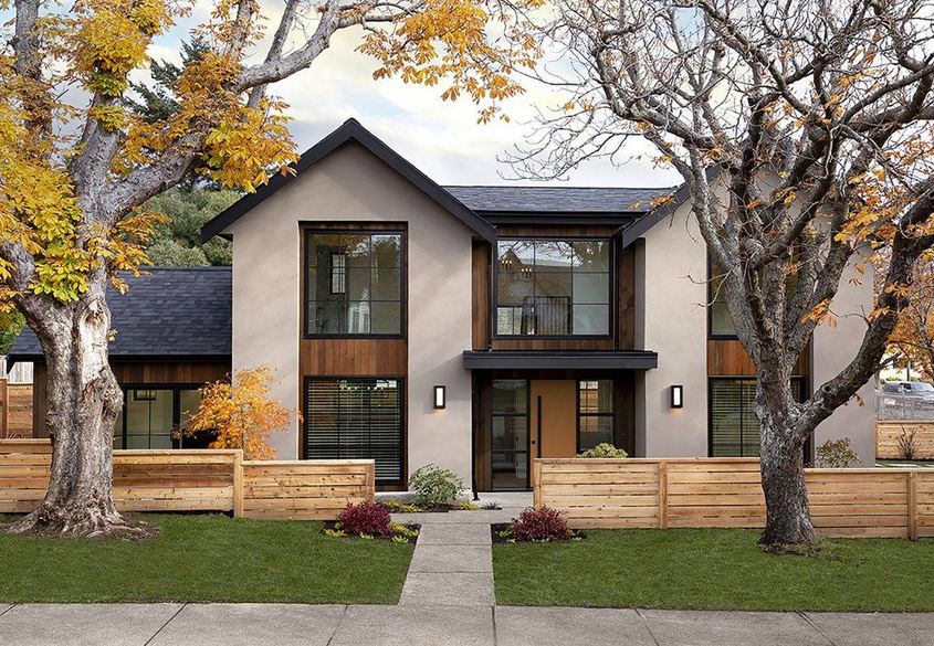 street view of a family home with modern, clean lines and a low horizontal wood fence, flanked by two mature trees