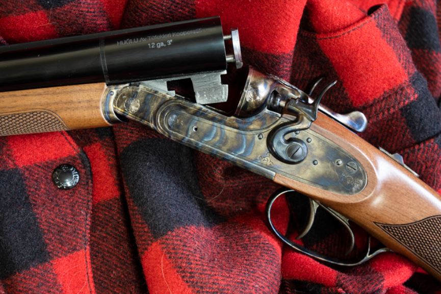 Detail view of a Huglu HRZ Turkish shotgun on a black and red checkered wool shirt or coat