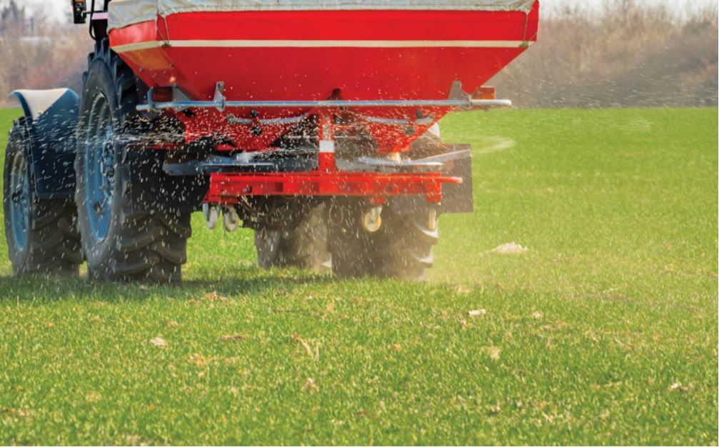 heavy farm equipment spraying fertilizer on a field