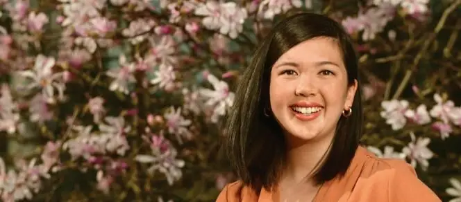 Author photo of Emily Chan smiling and standing in front of a blooming magnolia tree