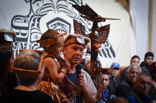 Chief Kwakwabalas holding a small child, both in traditional regalia, during a feast marking two years anniversary of the Swanson Island occupation