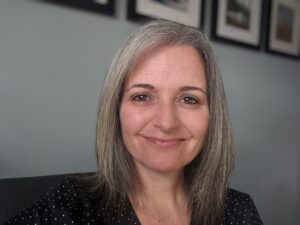 Colour portrait of Julie Fiorini against a wall with framed pictures at top