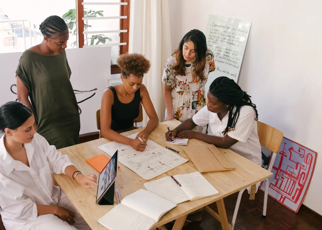 Group of diverse people working at a table with notebooks and other materials.