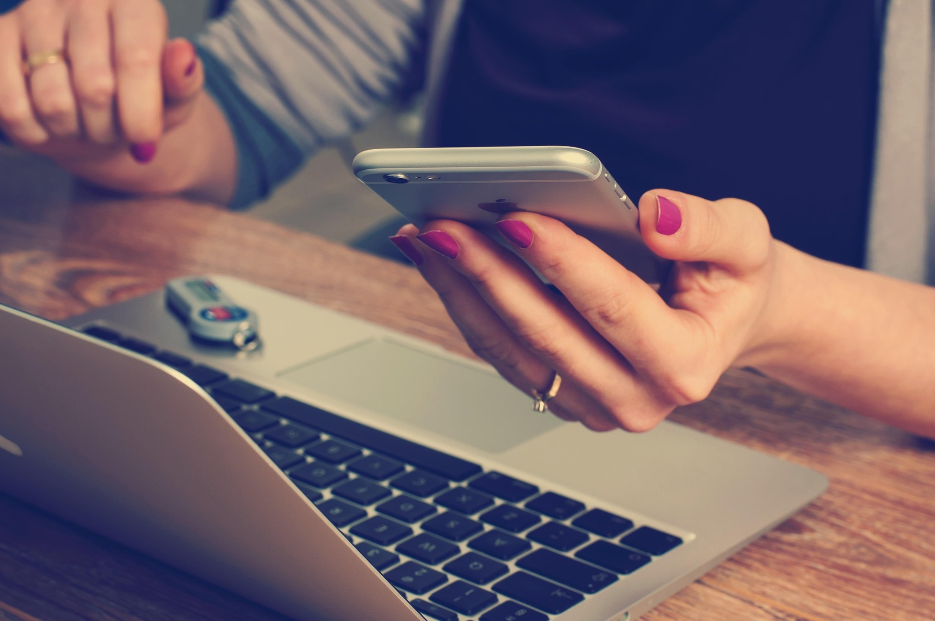Pixabay, office-620822_1920 by Firmbee: hand holding Iphone above a laptop