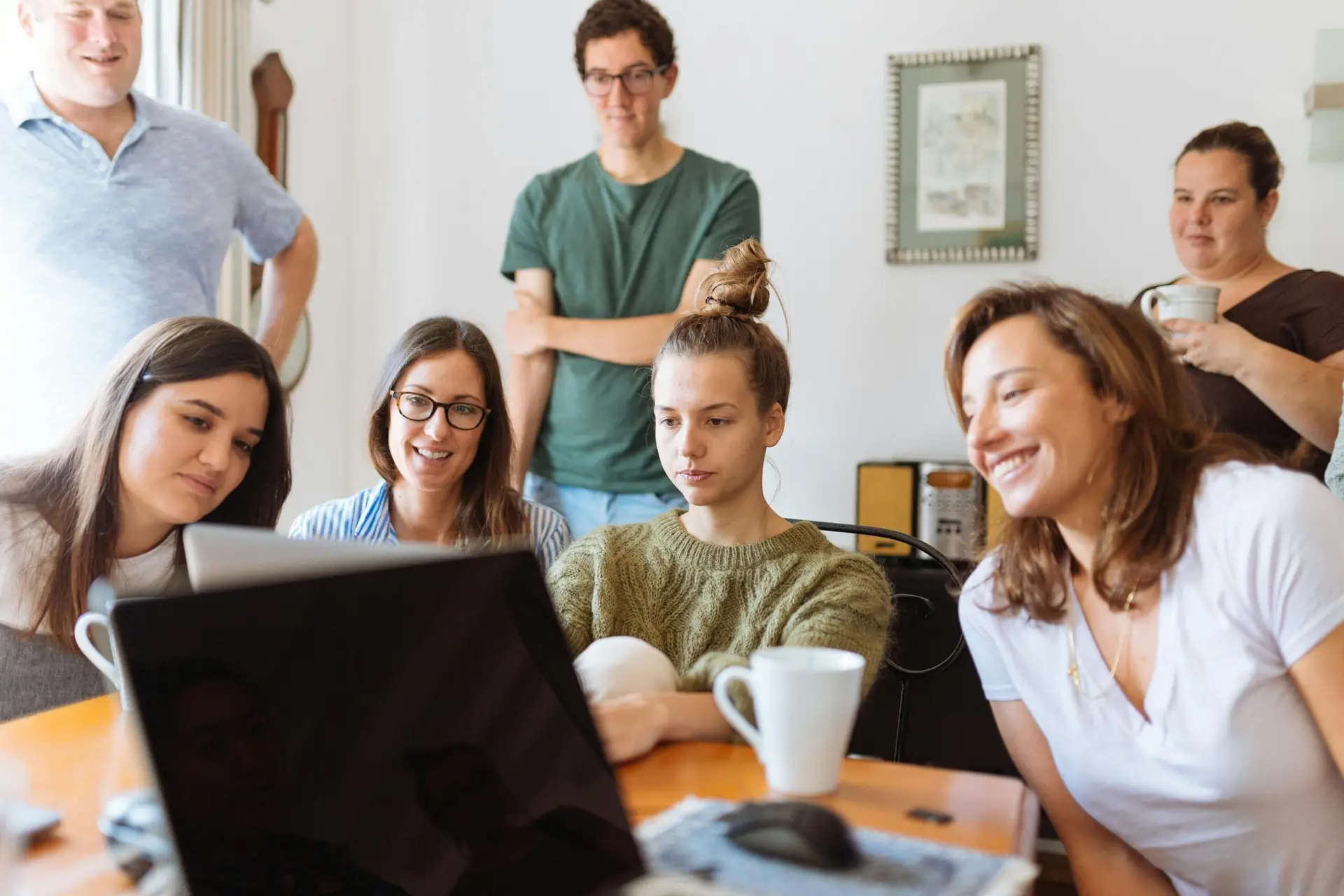 Pexels image by Hillary Fox: several men and women are gathered around a laptop looking at the screen in an office setting