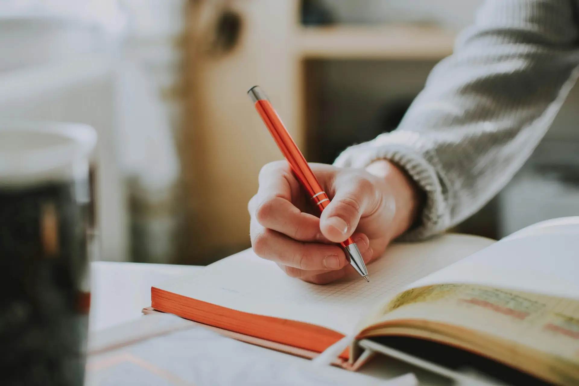 Pexels image by lil artsy: hand of a woman at a desk holding a pencil about a notebook