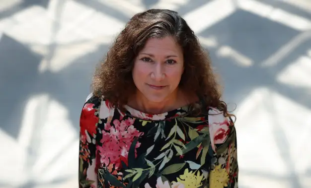 Fiona Bramble, standing portrait photographed from the top with an abstracted background of light and shadow, cropped image